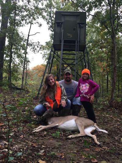 family with doe in front of fiberglass deer stand